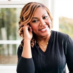 A woman is smiling while talking on a cell phone.