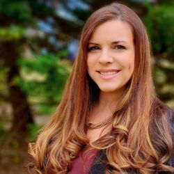 A woman with long brown hair is smiling for the camera.