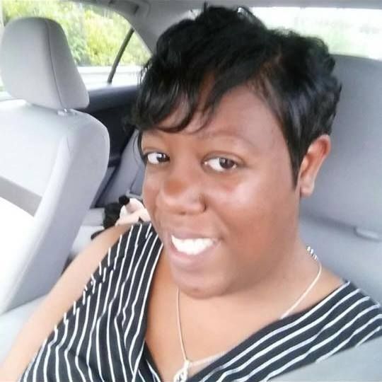 A woman is smiling while sitting in the back seat of a car