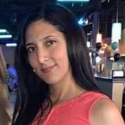 A woman in a pink tank top is standing in a restaurant.