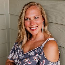 A woman in a floral off the shoulder top is smiling for the camera.