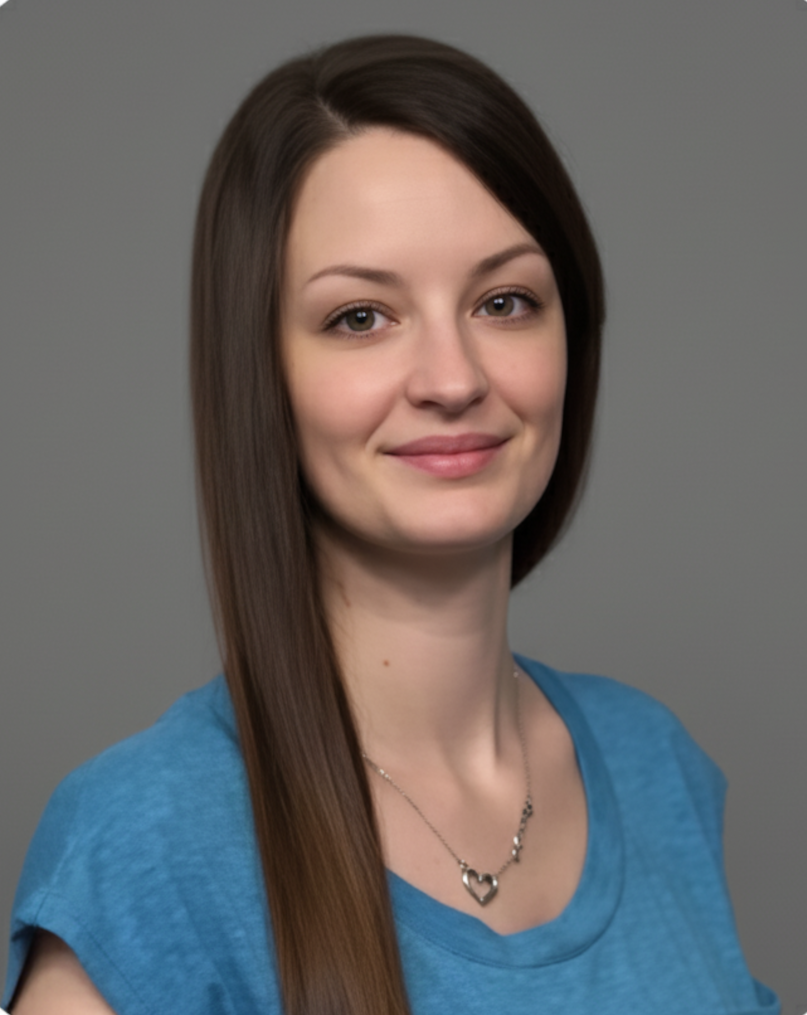 Woman with long brown hair, wearing a blue shirt and necklace, smiling, gray background.
