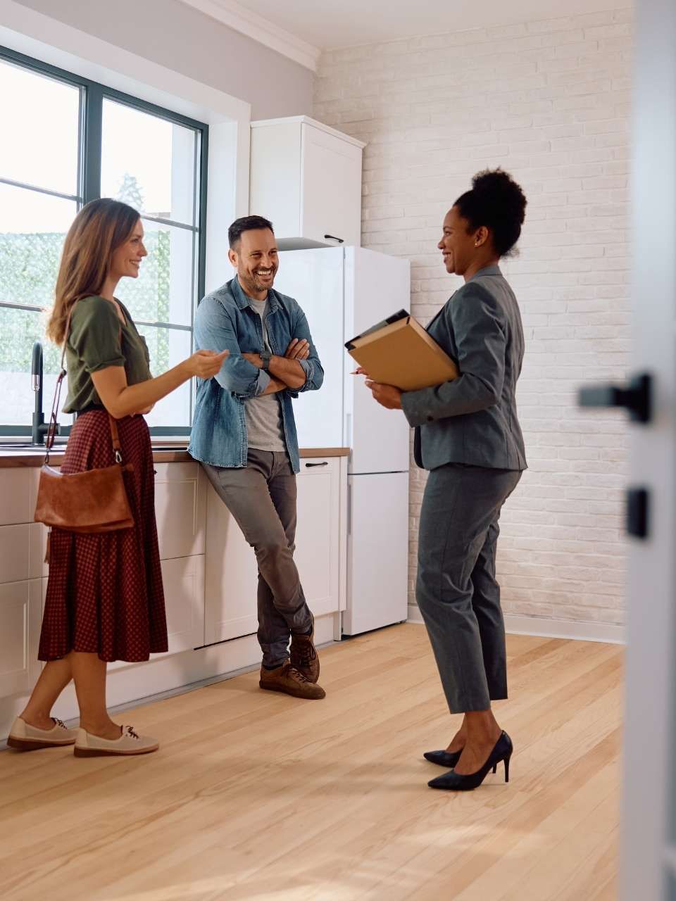 A woman is talking to a man and woman in a kitchen.