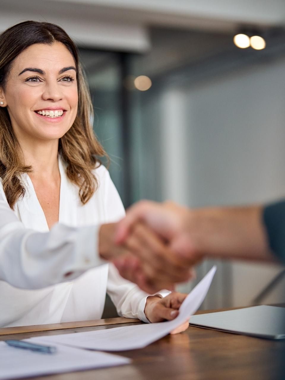 A woman is shaking hands with a man at a table.