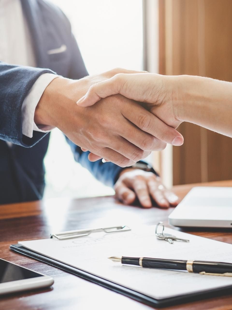 A man and a woman are shaking hands over a table.