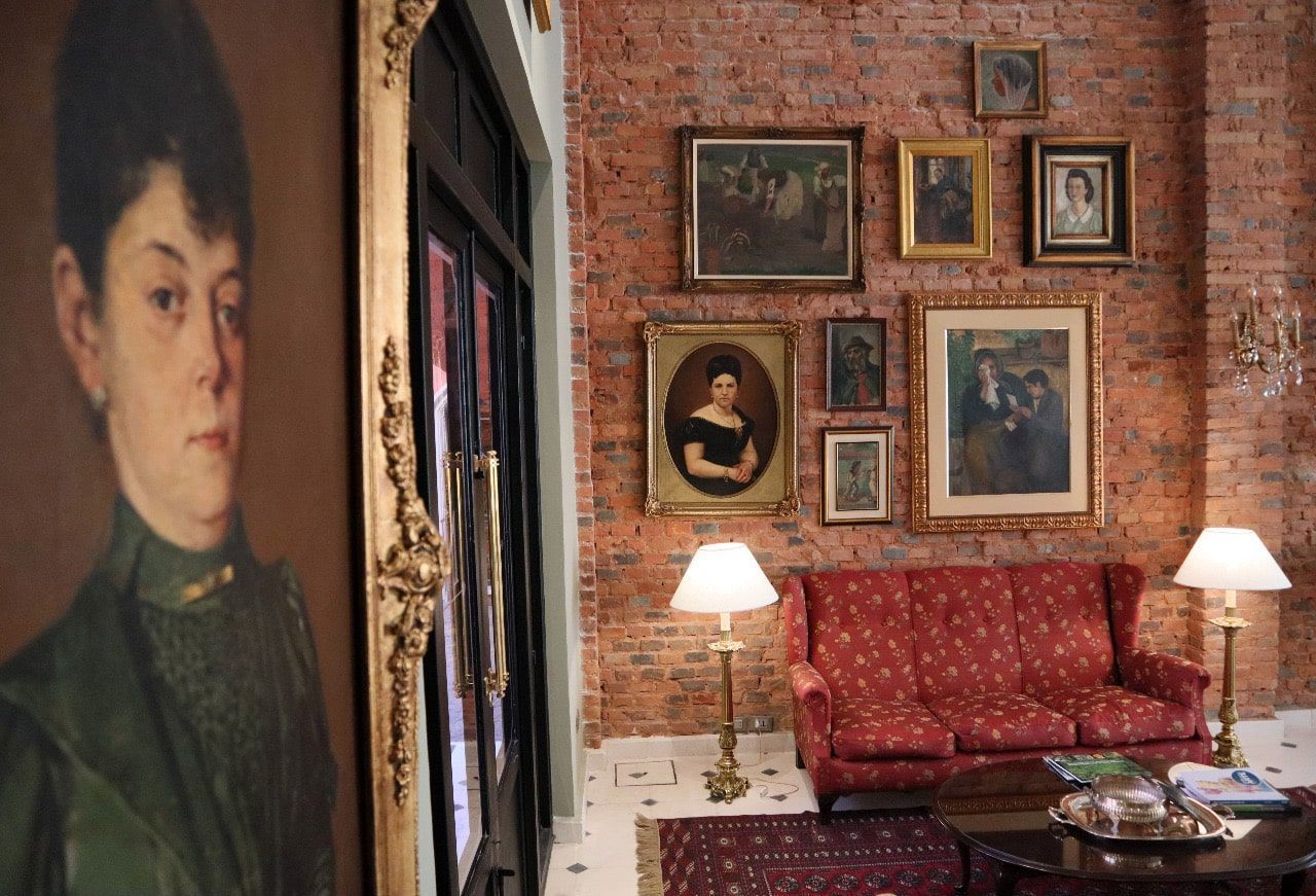 Sala de estar con pared de ladrillo, sofá, cuadros y retrato a la izquierda.