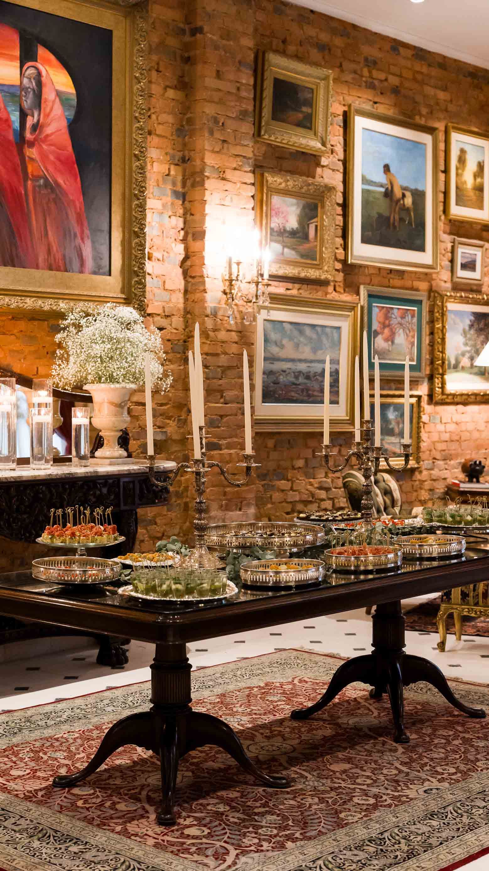 Mujer con vestido blanco dando vueltas en una habitación adornada con pinturas y una pared de ladrillos rojos.