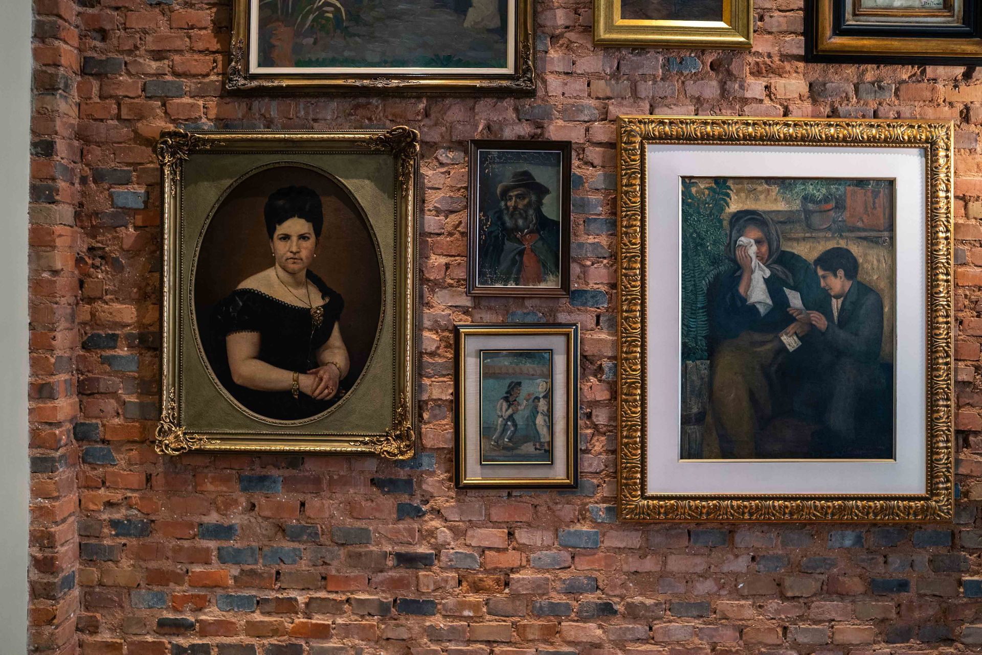 Reloj dorado adornado sobre una mesa con libros y un candelabro alto de latón en una habitación con una cortina roja.