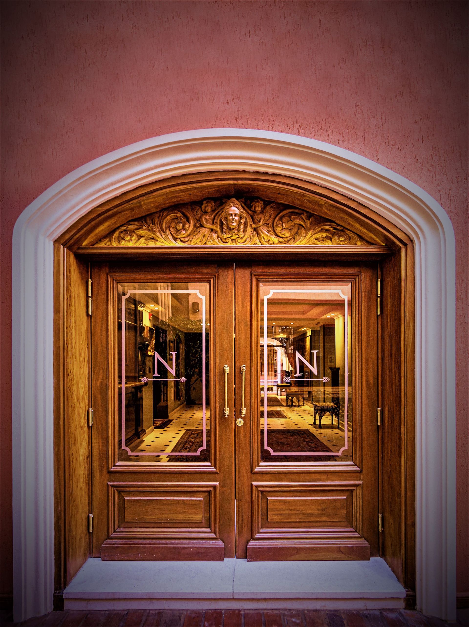 Puertas dobles de madera ornamentadas con paneles de vidrio; logotipo 