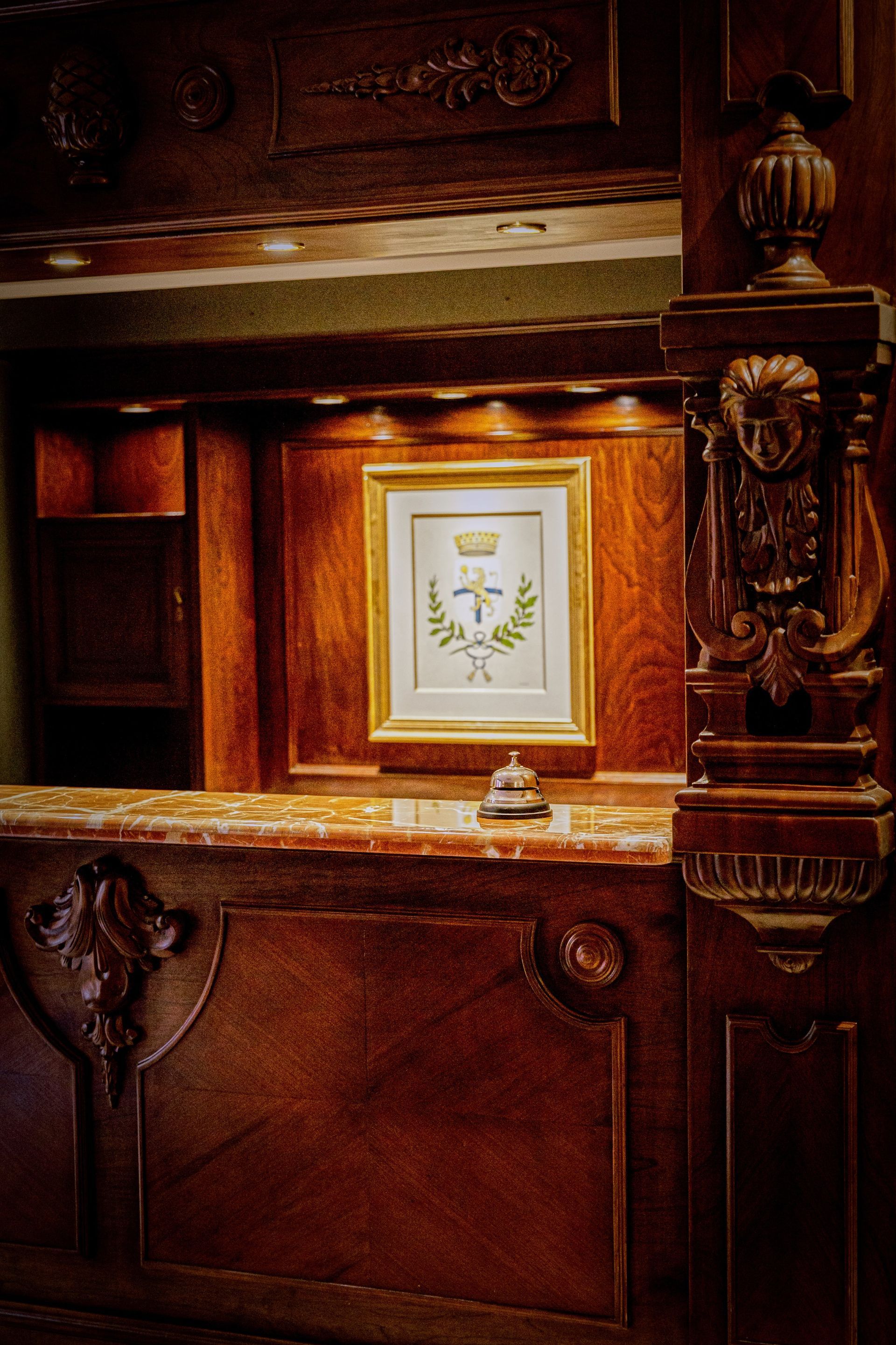 Mostrador de recepción de hotel de madera adornado con un emblema enmarcado y una campana.