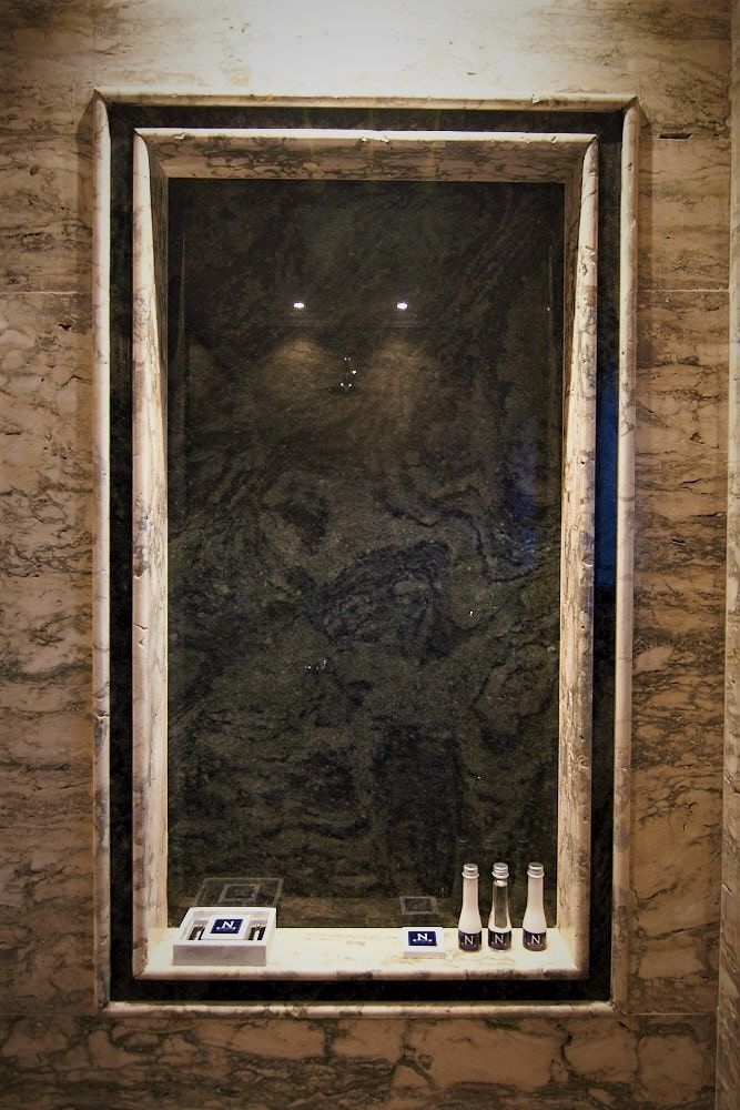 Cuadro de una alcoba de mármol empotrada con respaldo de piedra oscura.