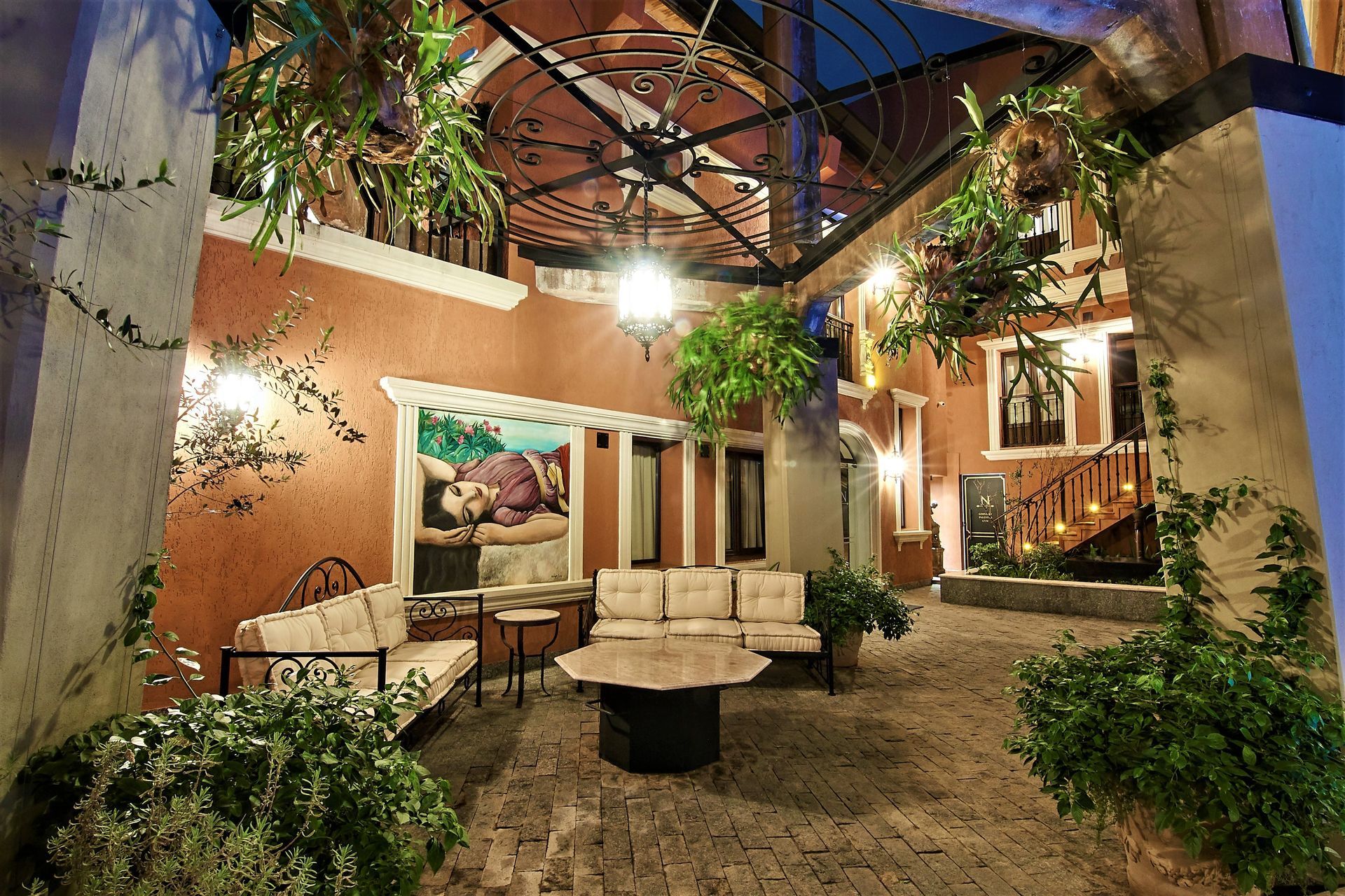 Patio con asientos, plantas y arte, con un techo de metal parcialmente abierto.