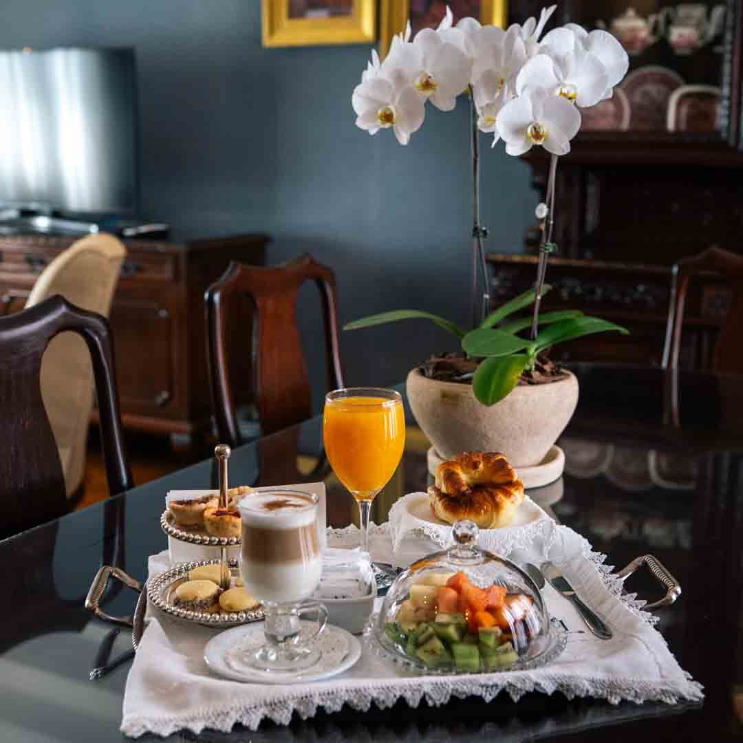 Un rincón acogedor con un sillón, cuadros y una mesita sobre una pared verde azulado. Suelo de madera.