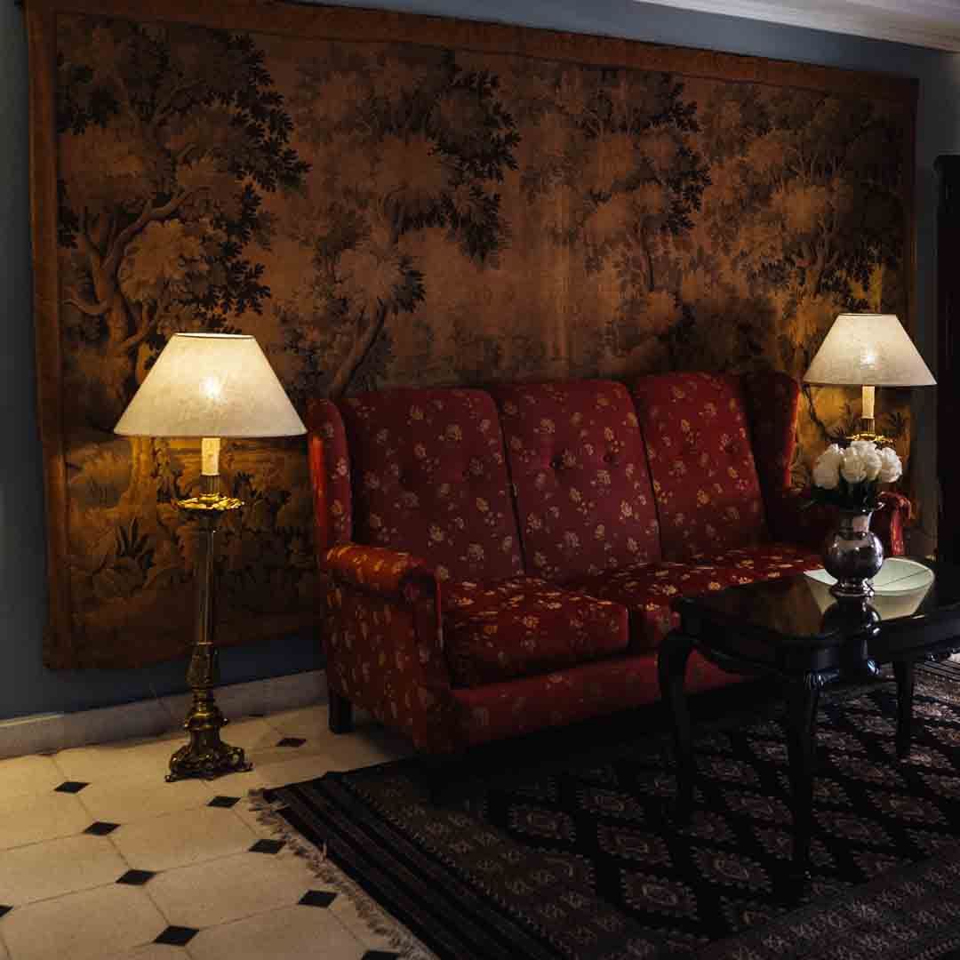 Habitación de hotel con dos camas individuales, bandeja de desayuno, escritorio y arreglo floral.