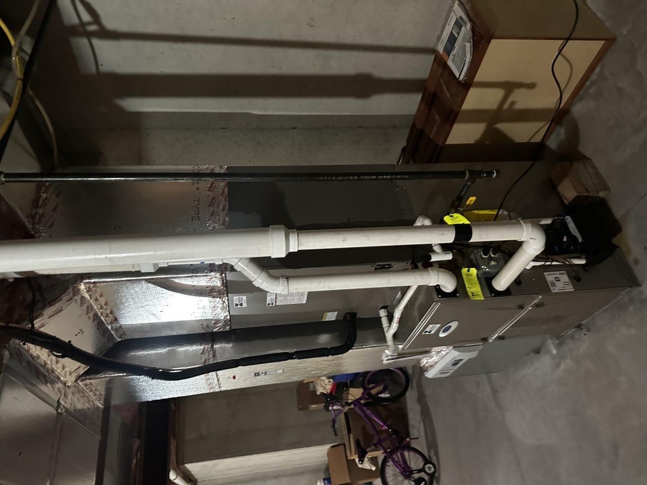 A high-efficiency furnace with white PVC intake and exhaust piping installed in a basement.