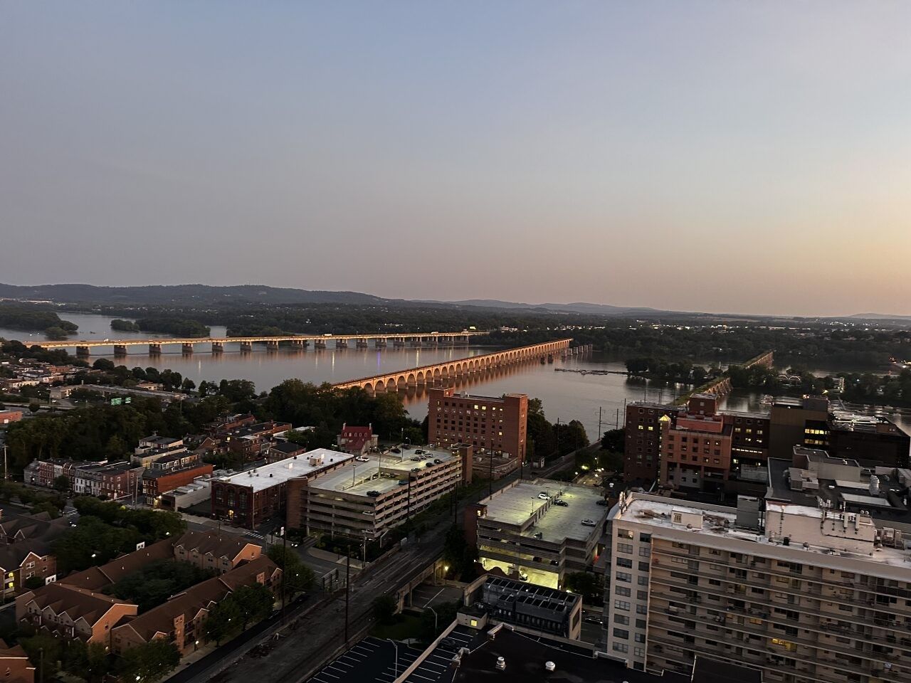 Aerial view of the Susquehanna River in Harrisburg, Pennsylvania, with illuminated bridges at sunset.