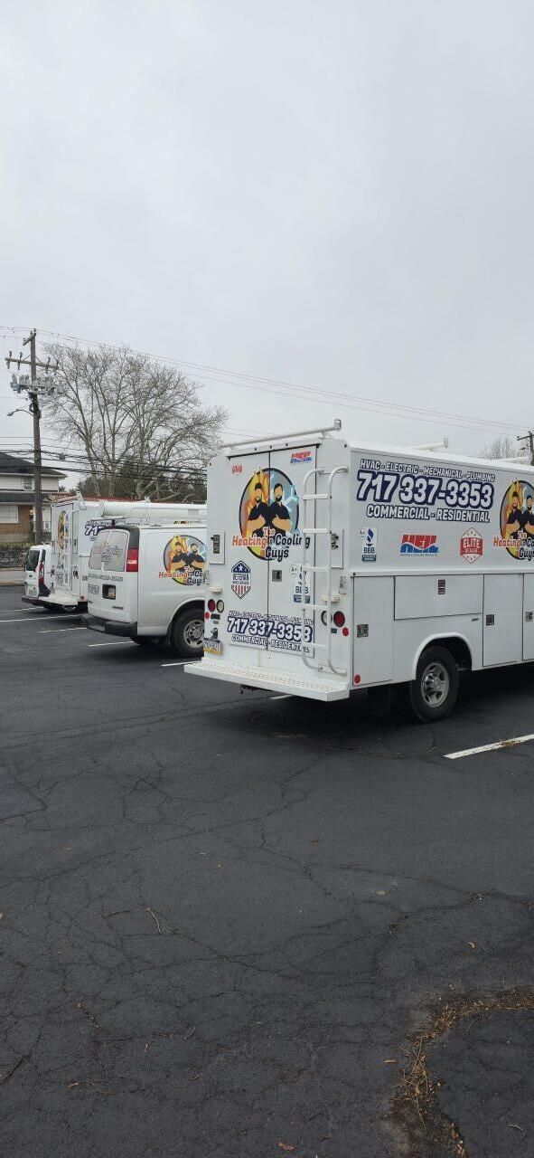 A row of white company service trucks parked in an asphalt lot under a cloudy sky.