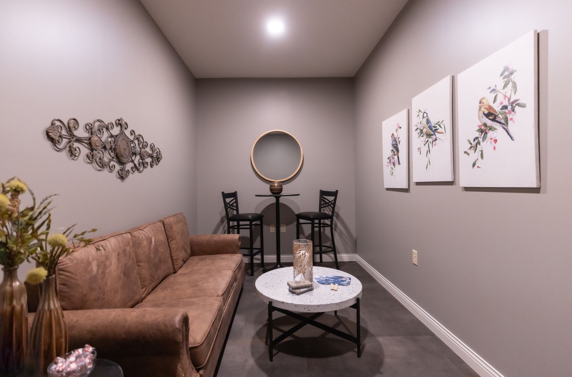 a living room with a couch , table , chairs and paintings on the wall .