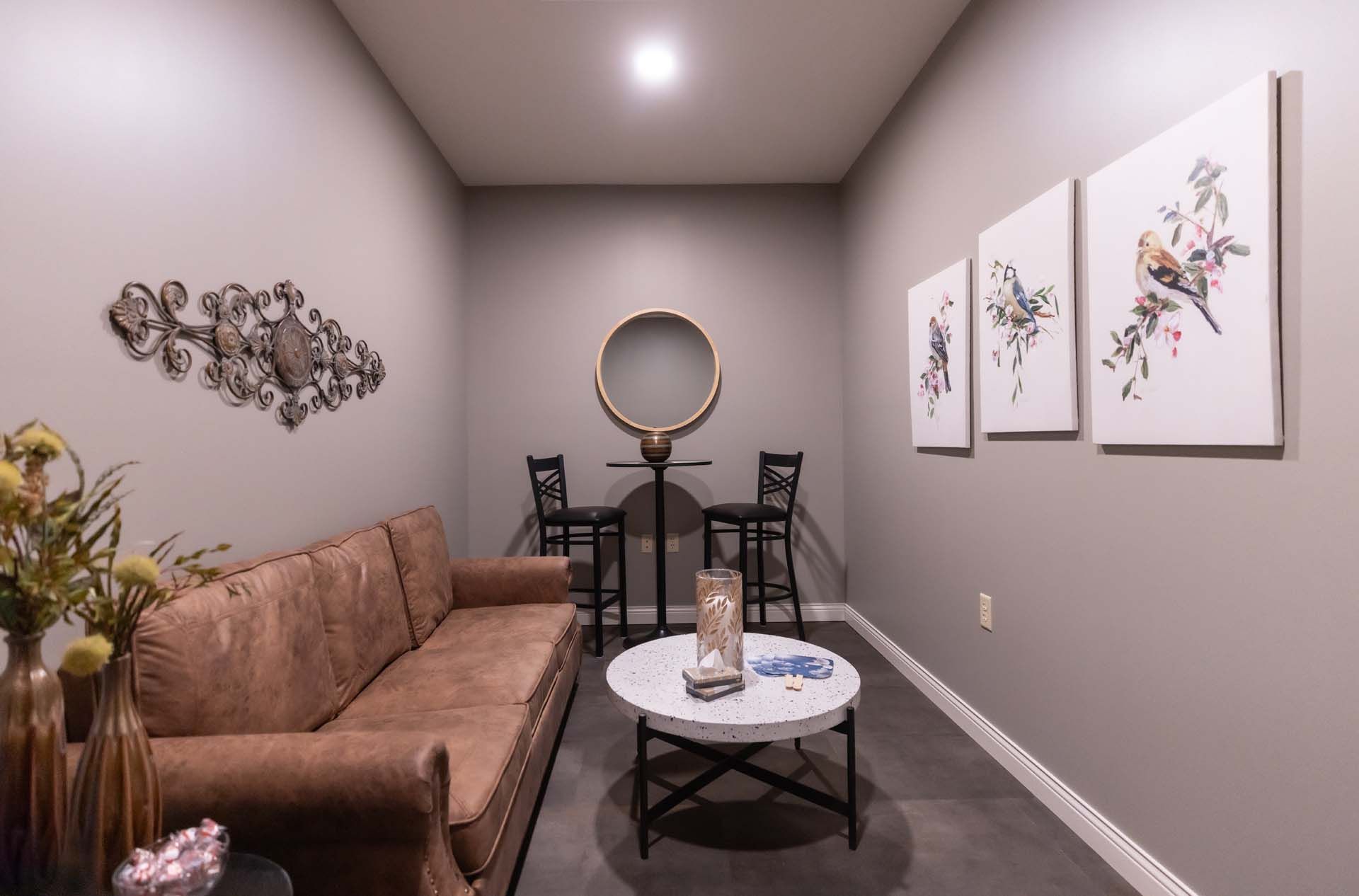 a living room with a couch , table , chairs and paintings on the wall .
