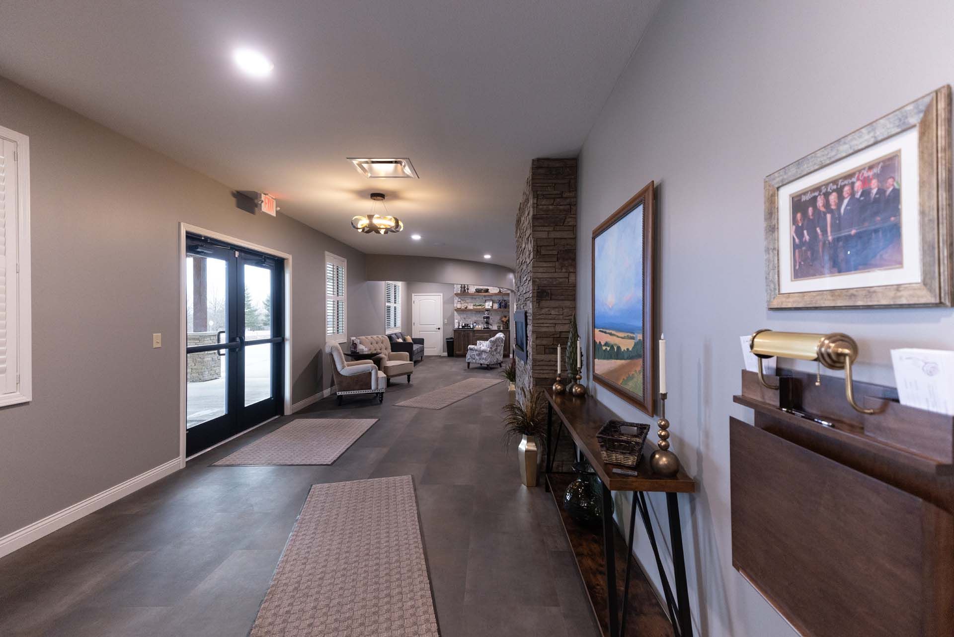 a long hallway in a house with a table and a painting on the wall .
