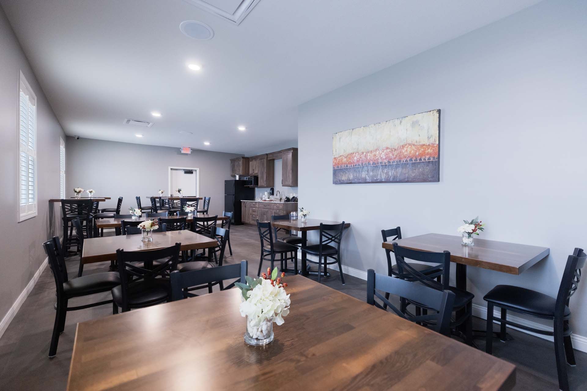 a dining room with tables and chairs and a vase of flowers on the table .