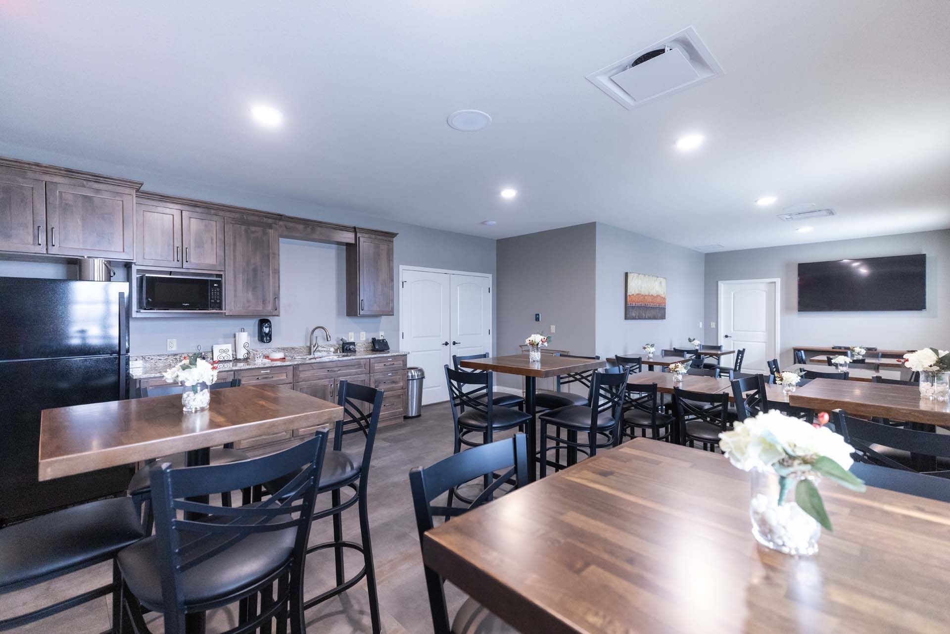 a large dining room with tables and chairs and a kitchen .