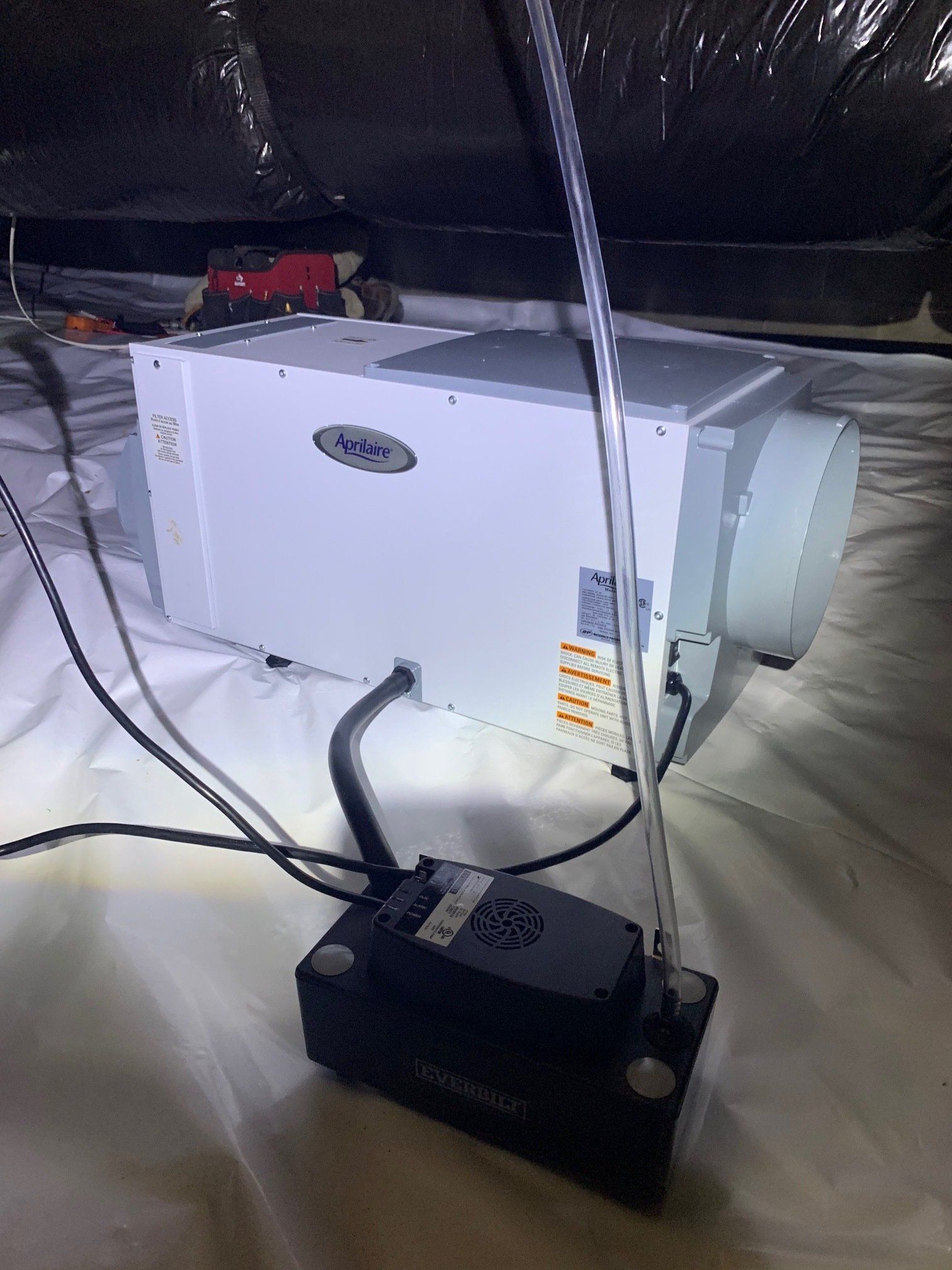 A white box with wires coming out of it is sitting on a bed.