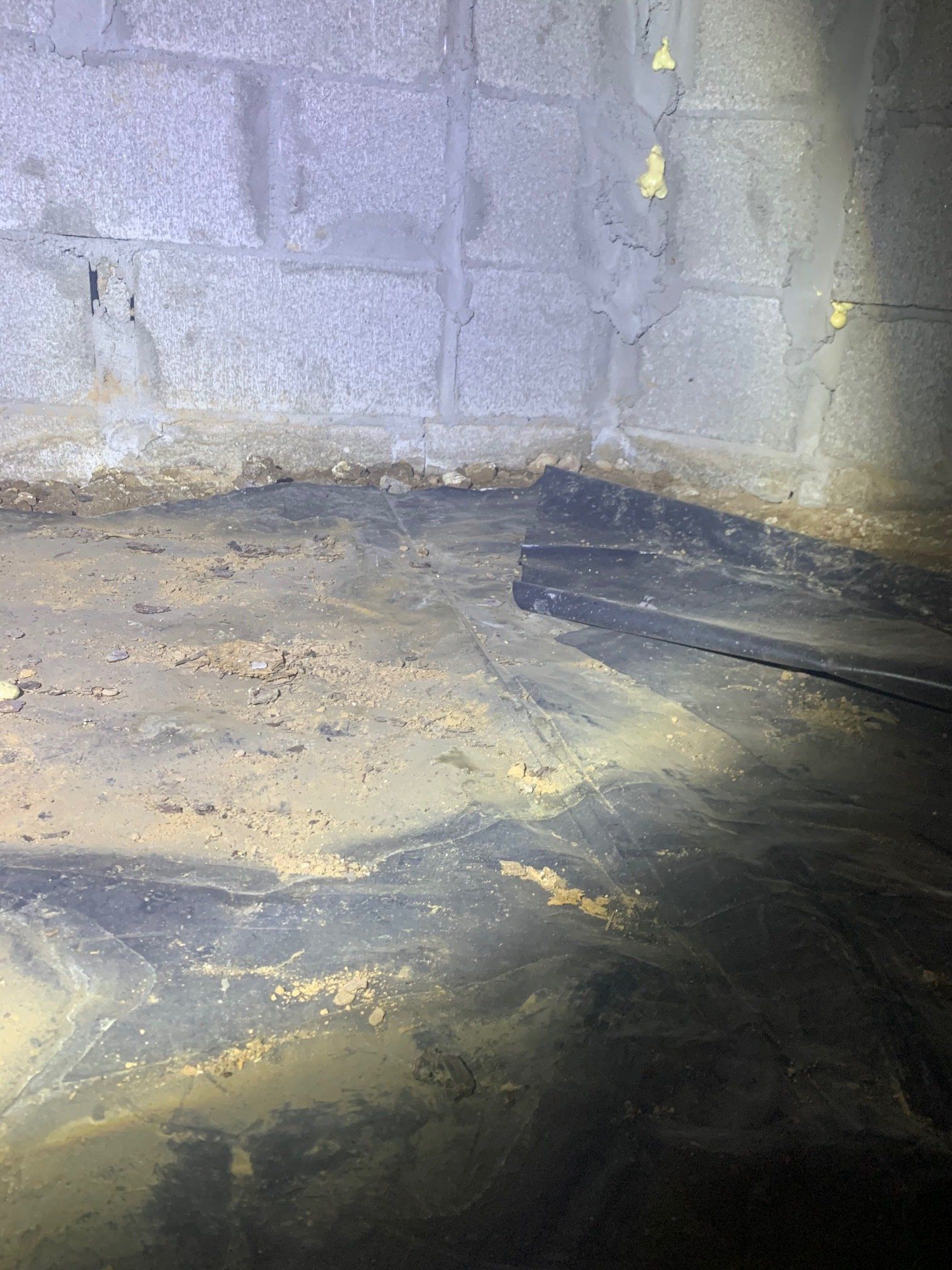 A dirty basement with a lot of dirt and a brick wall.