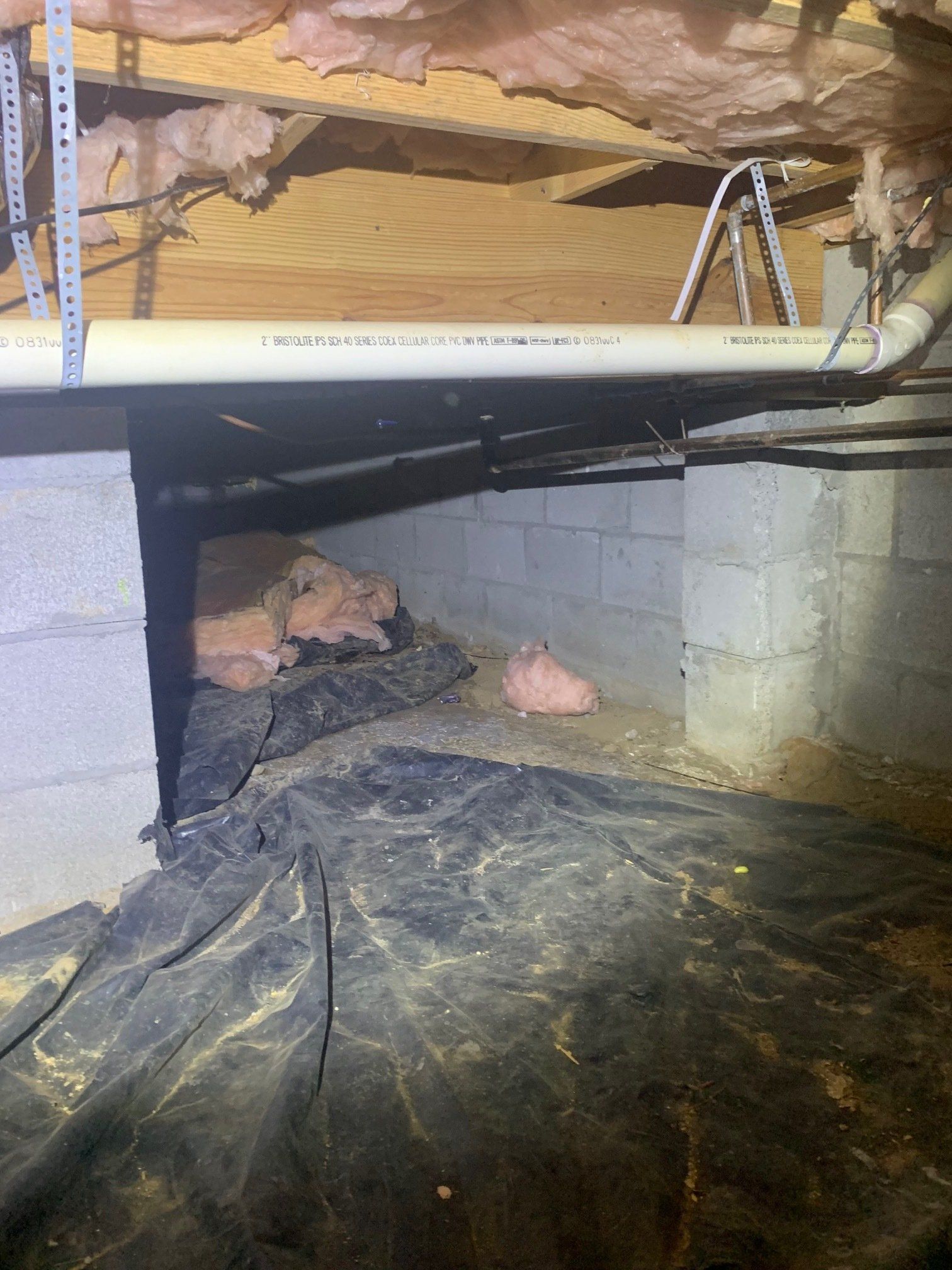 A basement with a lot of insulation and pipes in it.