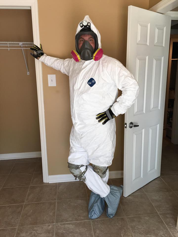 A man in a protective suit is standing in front of a door.