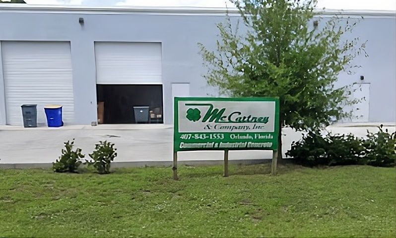 An individual wearing a red cap and blue-striped shirt driving a vehicle while looking out the side window.