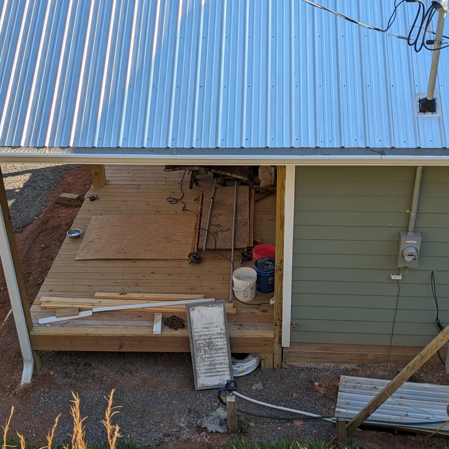 Deck under metal roof with building and construction materials.
