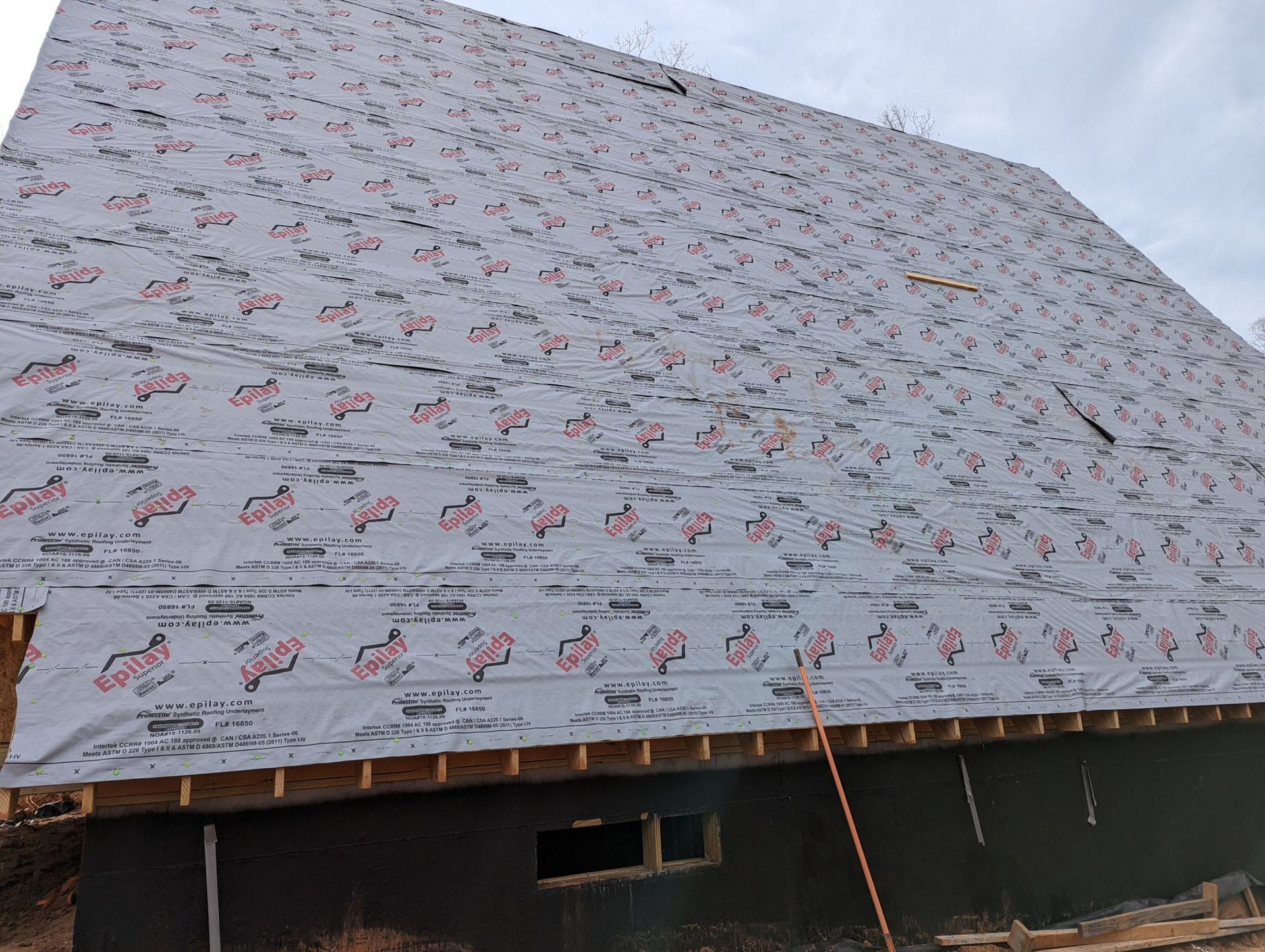 Roofing underlayment installed on a partially constructed building's roof.