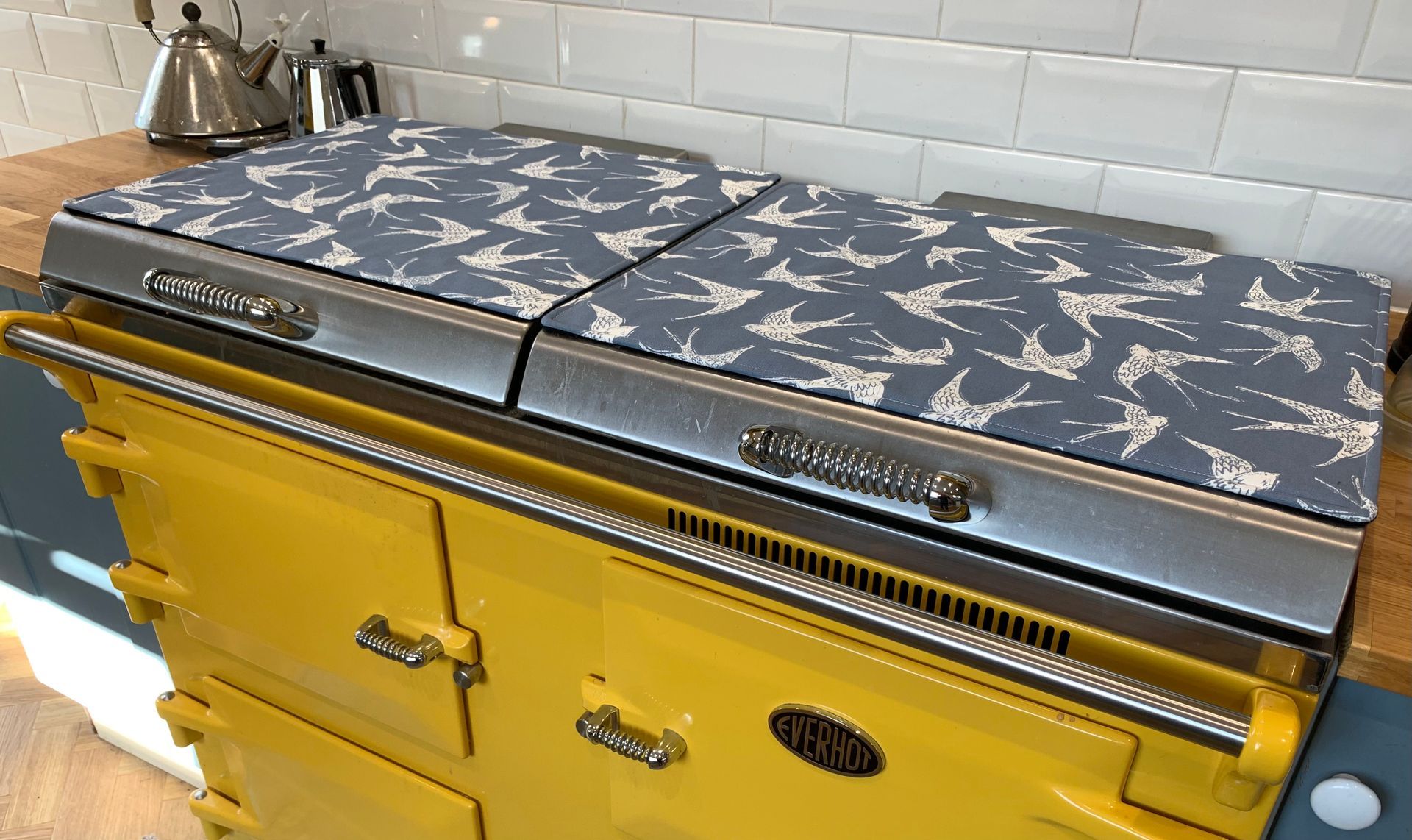 A yellow stove top oven with a pattern on it is in a kitchen.