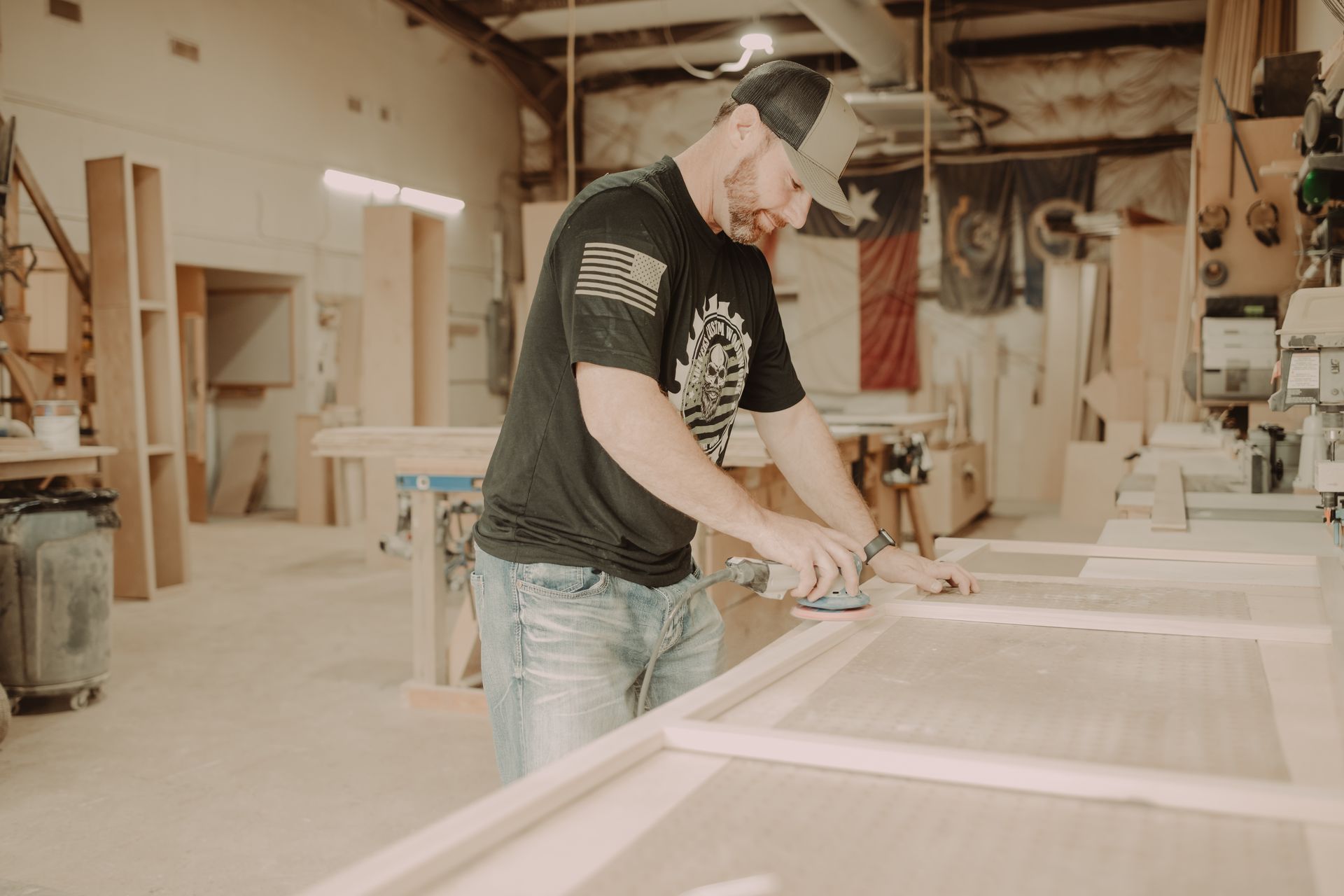 A man is sanding a piece of wood in a workshop.