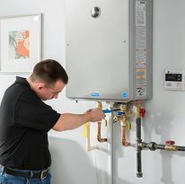 Man adjusting a wall-mounted boiler with pipes and gauges in a home utility room