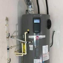 Gray water heater with pipes and vents mounted against a wall in a utility room