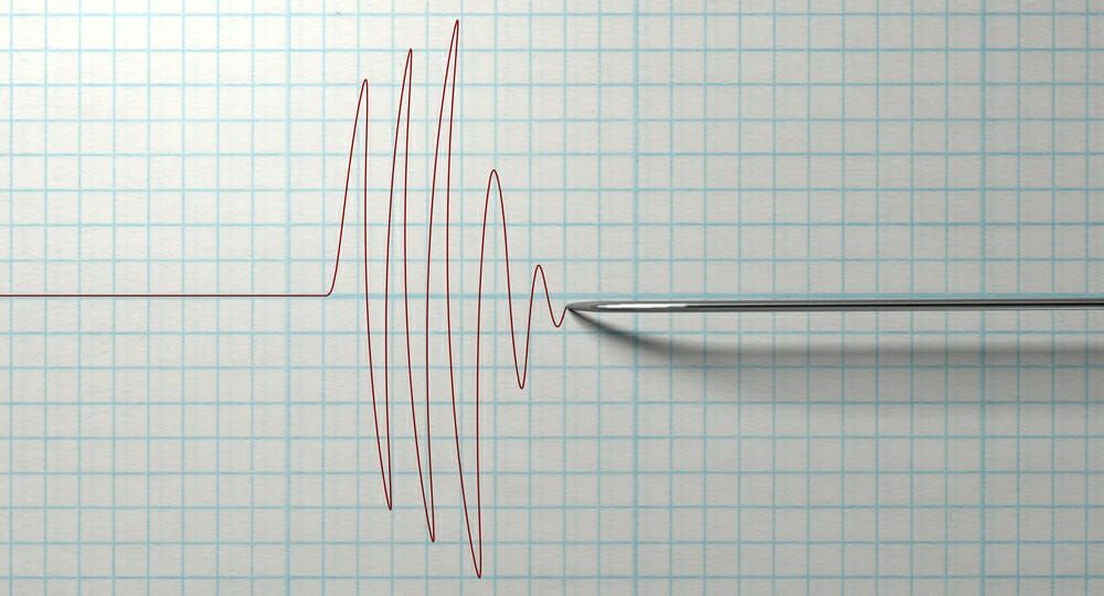 Seismograph recording of seismic waves: red line fluctuating, ending with a gradual decline on a graph paper.