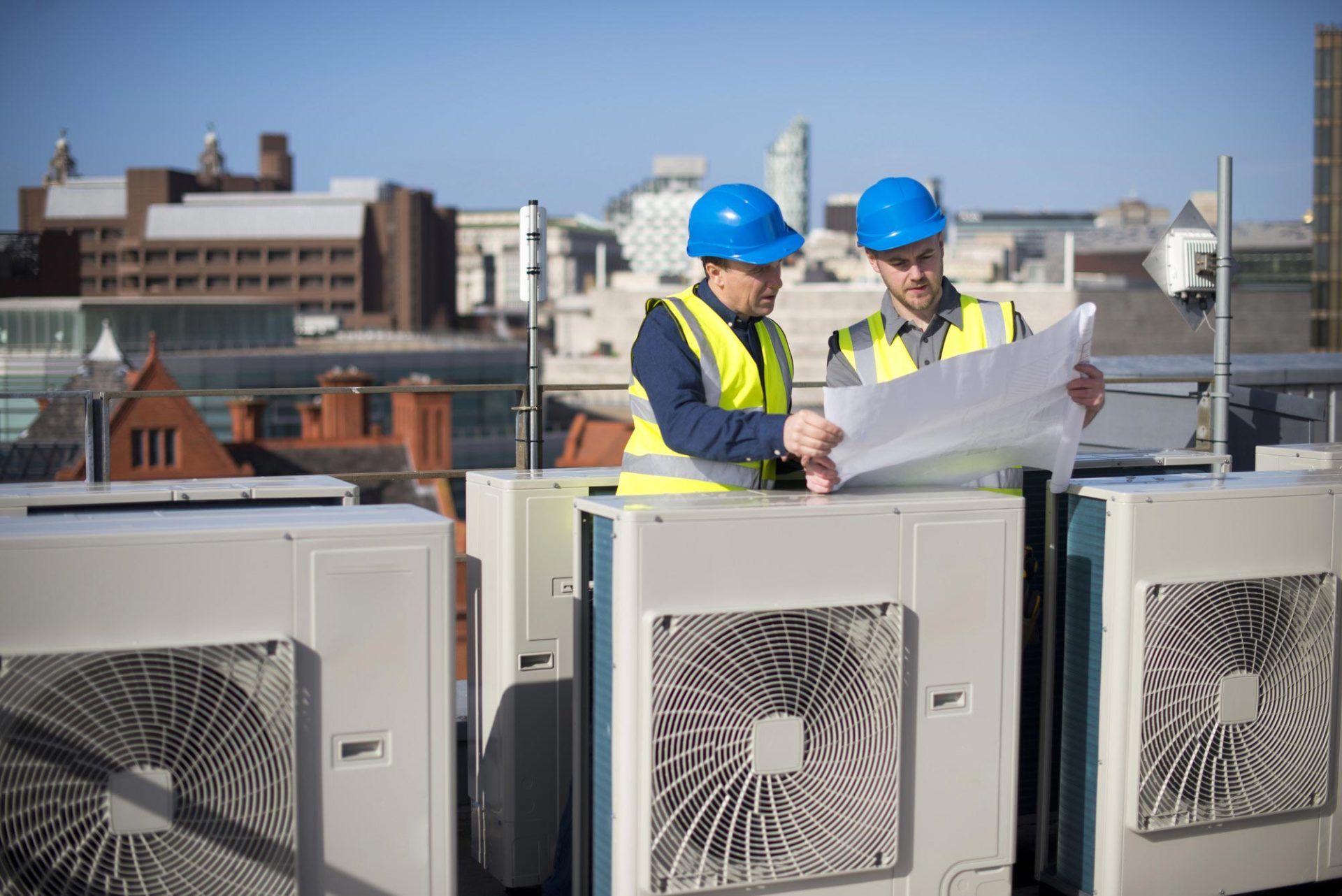 engineers looking at plans next to air conditioning units