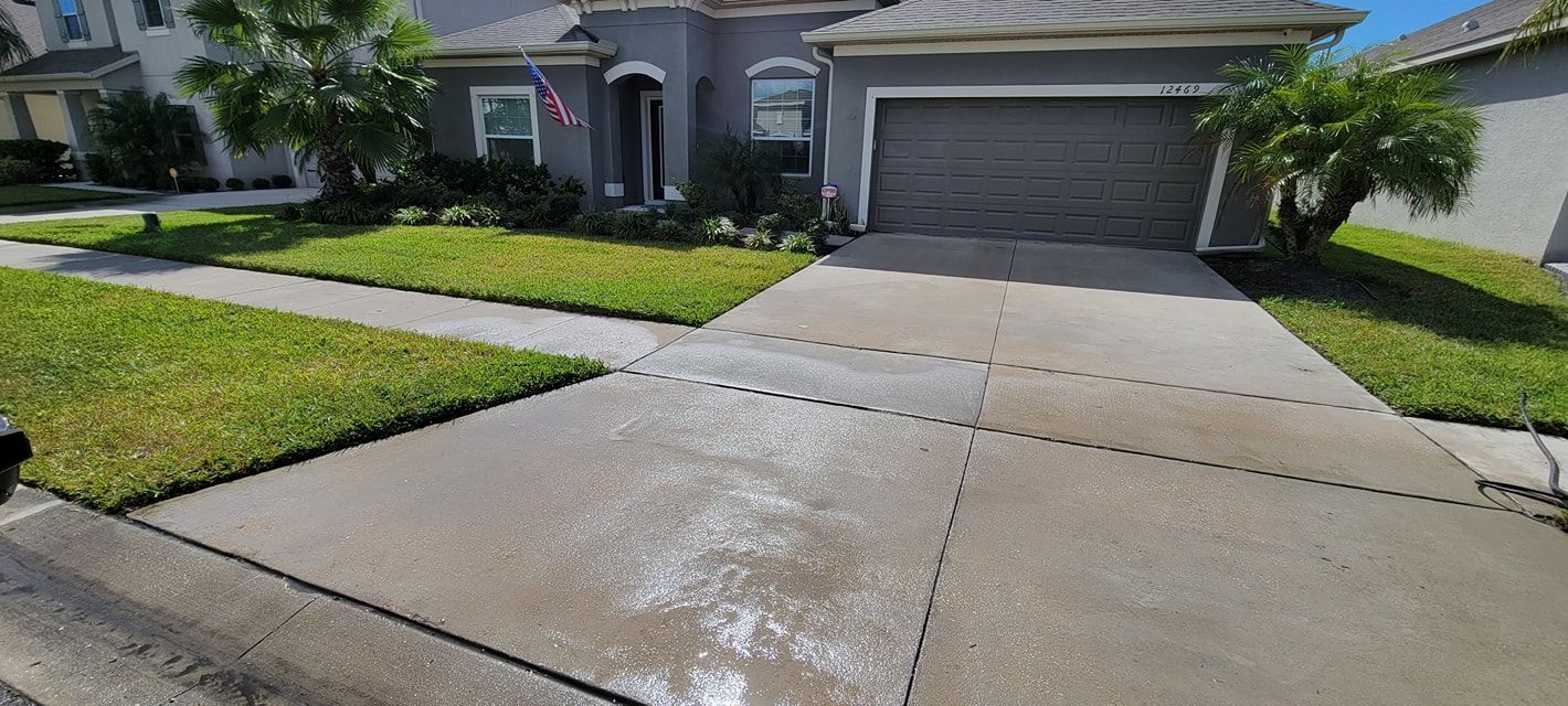 A house with a driveway and green lawn. Driveway has white residue on it.