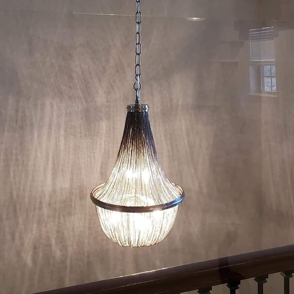 A decorative chandelier with a textured shade is suspended from a chain.