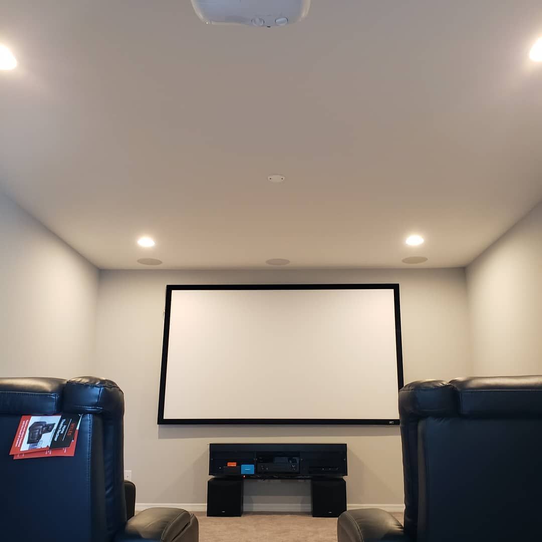 Home theater with a screen, speakers, and reclining chairs.