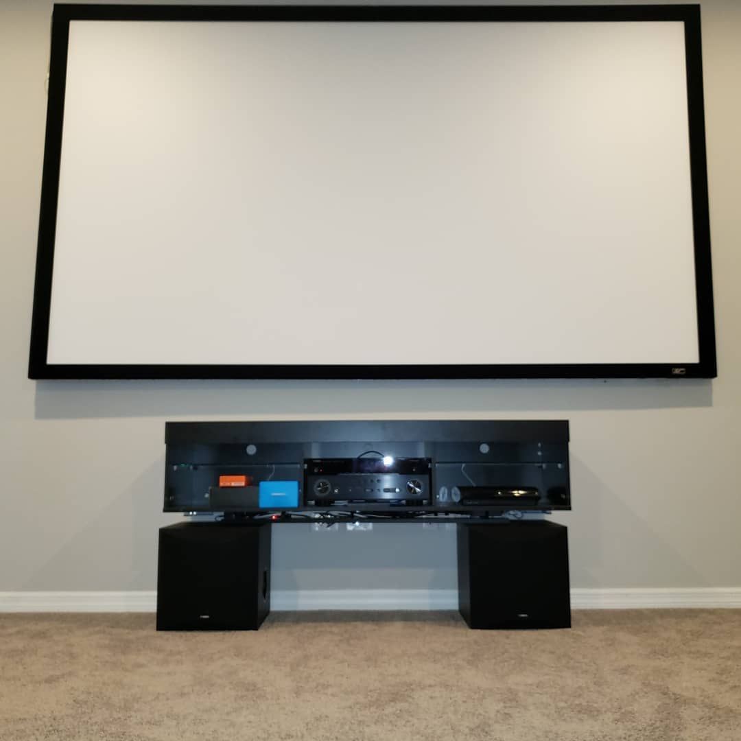Home theater setup with a large screen, black speakers and media center.