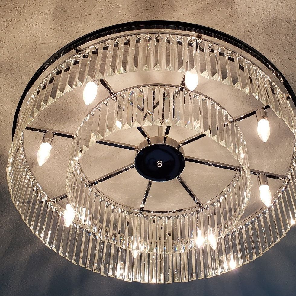 Circular crystal chandelier with multiple lights, black and silver frame.