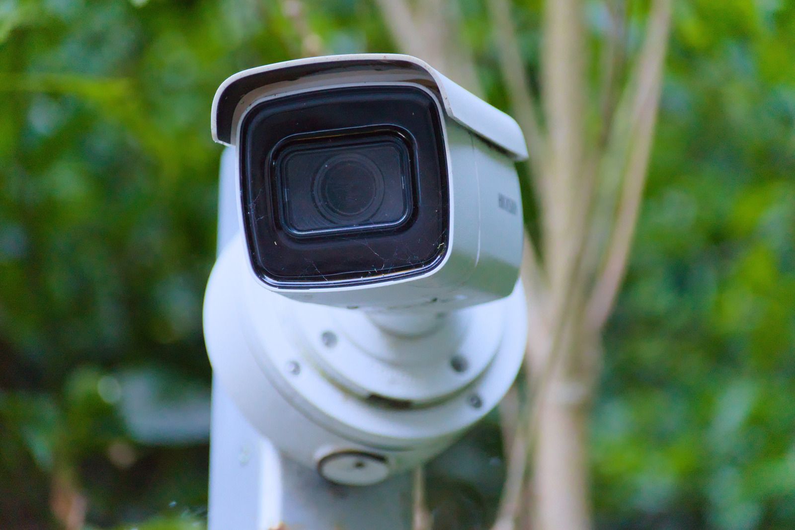 White security camera mounted on a pole, focused on viewer, with a green background.