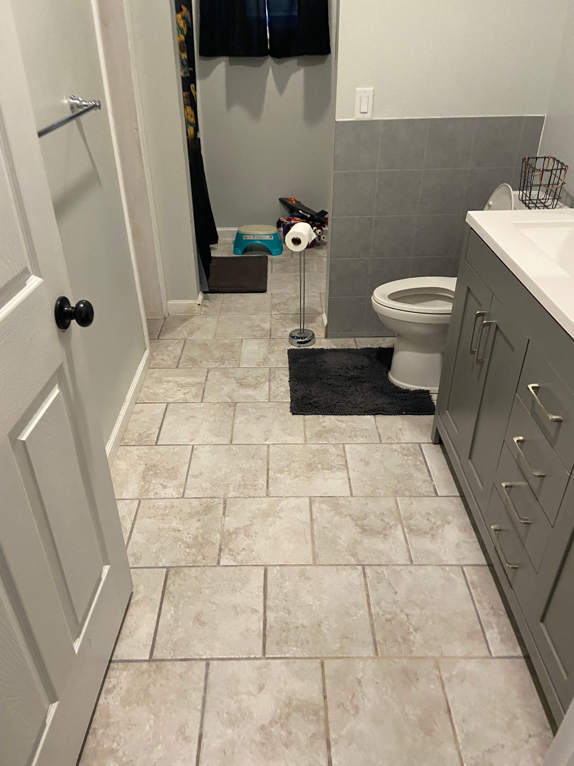 A bathroom with a toilet , sink , and tile floor.