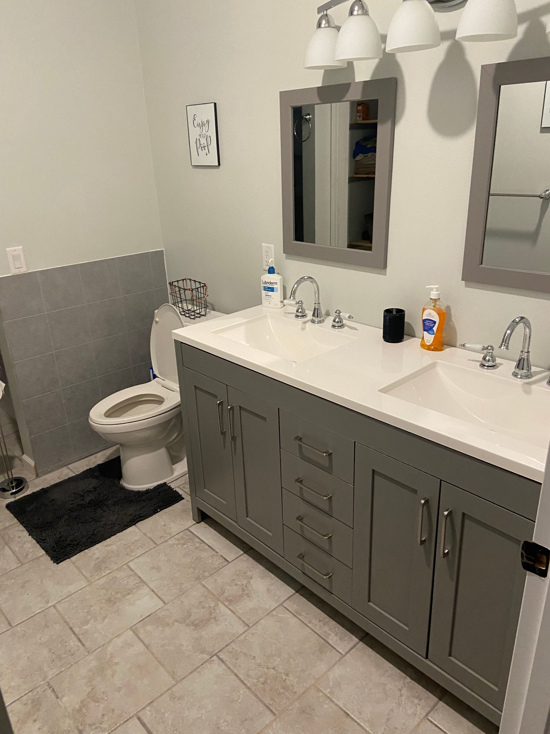 A bathroom with two sinks , a toilet and two mirrors.