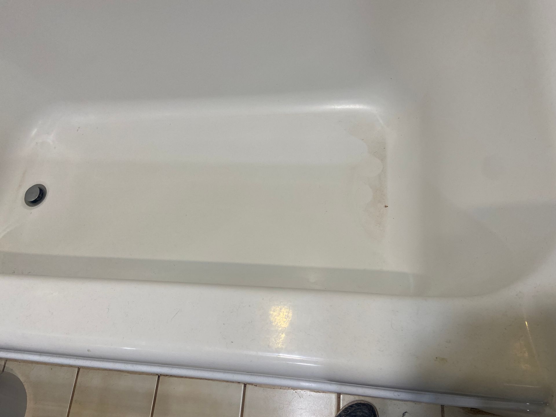 A white bathtub is sitting on a tiled floor in a bathroom.