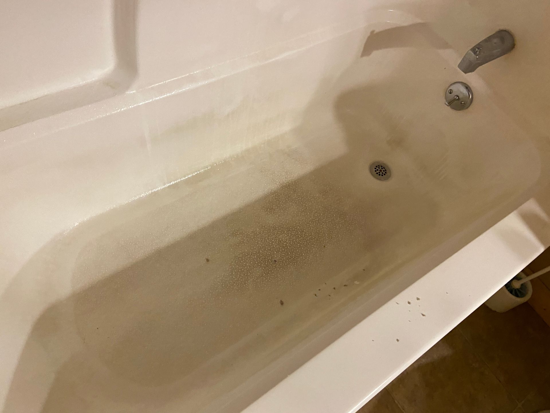 A bathtub filled with water and soap in a bathroom.