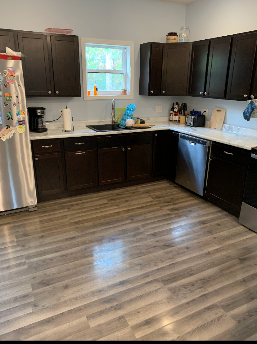 A kitchen with stainless steel appliances and wooden floors.